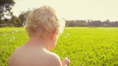 Baby-boy-blowing-soap-bubbles-outdoors